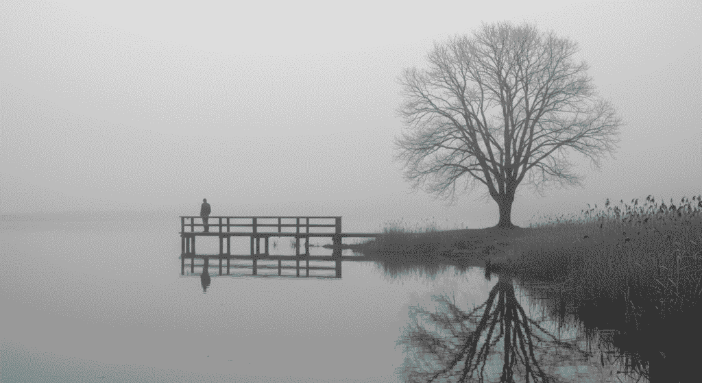 La Llorona: leyenda, origen y misterio detrás del fantasma más famoso 4 Persona solitaria en muelle con niebla. Imagen de soledad y melancolía.