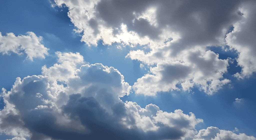 Cielo azul con nubes blancas y rayos de sol filtrándose. Ideal para temas de naturaleza, clima y bienestar.

