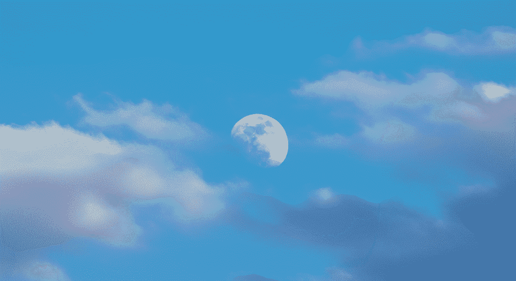 Imagen de la luna creciente en un cielo azul con nubes dispersas. Foto de astronomía ideal para calendarios, fondos de pantalla y contenido educativo.

