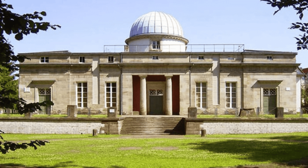 Observatorio astronómico con cúpula blanca. Arquitectura clásica en entorno natural.

