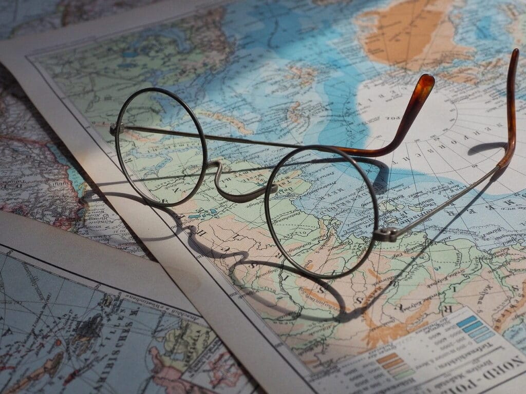El enigma del Asesino del Zodiaco: Un misterio que podría haberse resuelto 2 Mapa con gafas: Un mapa mundial extendido con unas gafas redondas apoyadas sobre él, evocando una atmósfera de exploración y viajes.