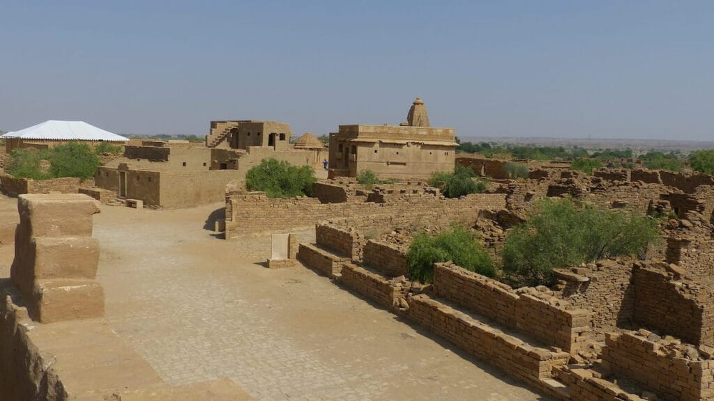 Lugares prohibidos donde el terror es real 11 Ruinas del pueblo de Kuldhara en India, mostrando casas de barro deshabitadas en un paisaje árido bajo un cielo despejado.