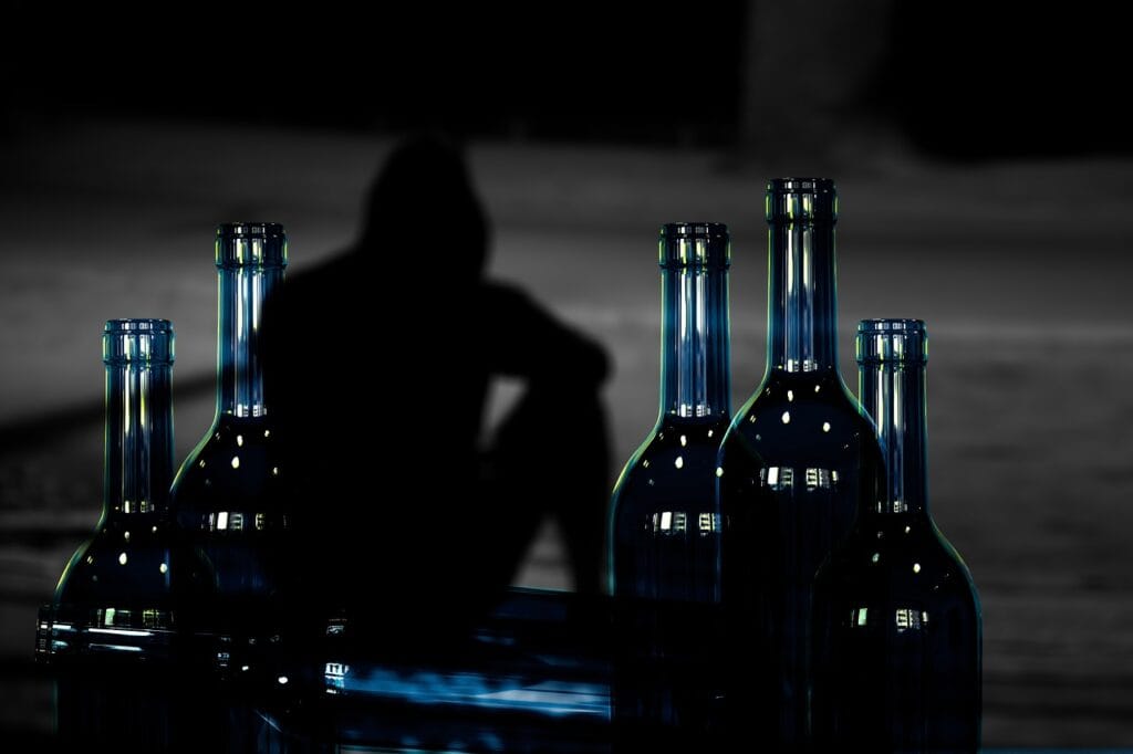 ¿Por Qué el Alcohol Nos Hace Perder la Memoria? 5 Silueta con botellas: imagen de soledad y depresión. Bebidas alcohólicas y salud mental.