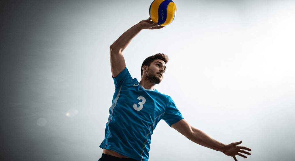 ¿Qué es el Voleibol? Reglas, Técnicas y Curiosidades 7 Jugador de voleibol masculino a punto de golpear la pelota en un fondo blanco brillante. Deporte y acción en primer plano.