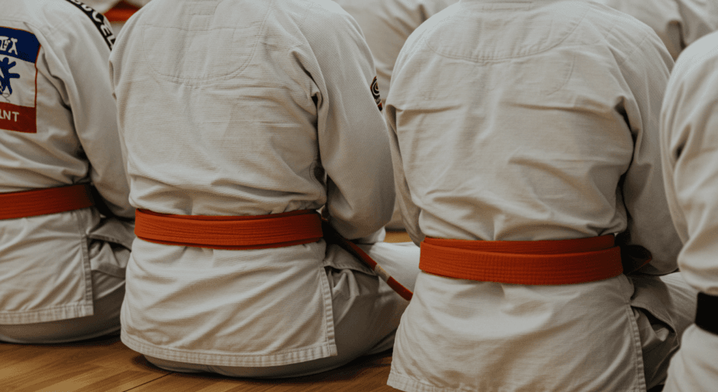 Clase de karate con cinturones naranjas. Detalle de kimonos blancos con cinturones de karate naranjas. Ideal para promoción de artes marciales y disciplina.