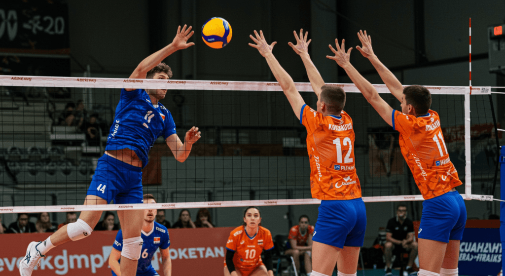¿Qué es el Voleibol? Reglas, Técnicas y Curiosidades 2 Jugadoras de voleibol compitiendo en un partido, una intentando rematar y otra bloquear. Acción deportiva.