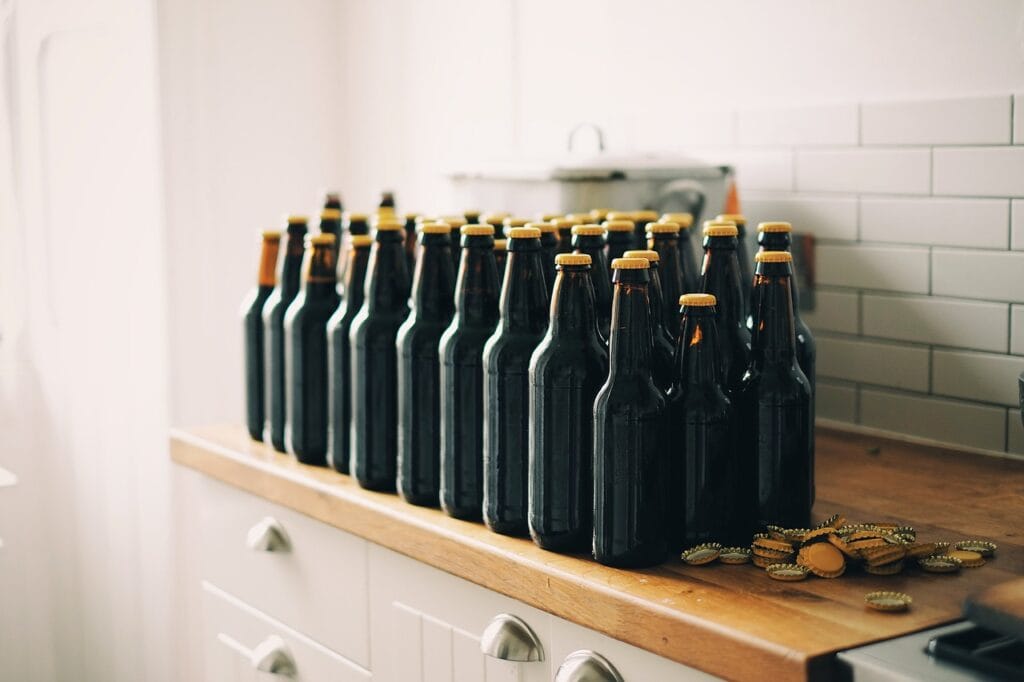 ¿Por Qué el Alcohol Nos Hace Perder la Memoria? 7 Botellas de cerveza casera alineadas en cocina.