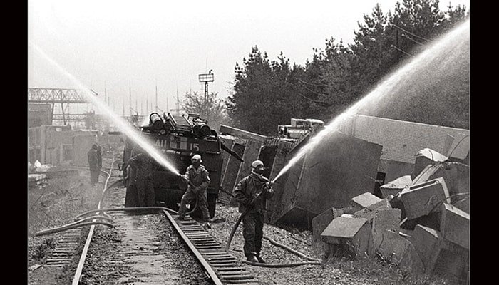 Chernóbil: La Tragedia Nuclear Que Marcó al Mundo 3 Imagen en blanco y negro muestra trabajadores descontaminando escombros radiactivos con mangueras en las vías del tren en Chernóbil durante las labores de limpieza.
