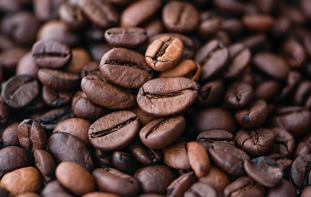 6 Cosas que Probablemente No Sabías sobre el Café (Pero Deberías Saber) 1 Primer plano de granos de café tostados, con texturas detalladas y tonos marrones resaltados por la iluminación.