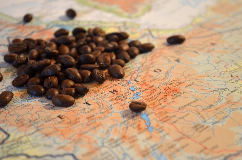 6 Cosas que Probablemente No Sabías sobre el Café (Pero Deberías Saber) 2 Granos de café sobre un mapa geográfico, destacando la conexión entre el café y su origen global.