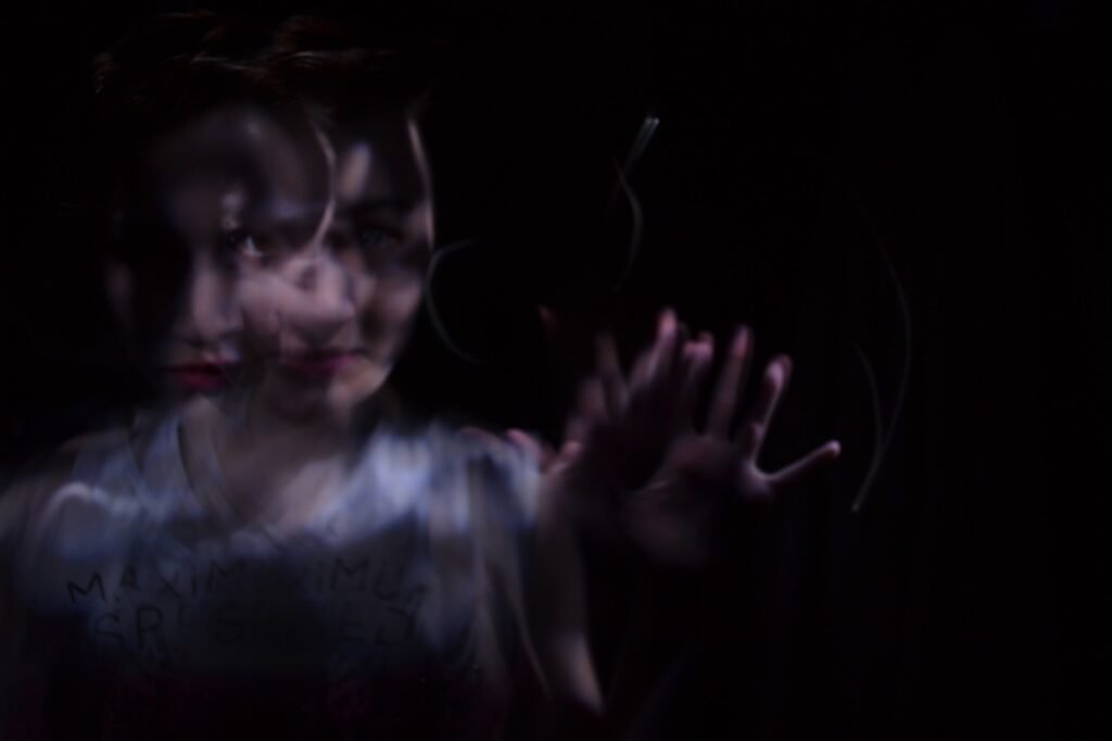 Trastornos de la Conducta Alimentaria: Lo Que Nadie Te Cuenta 3 Foto artística borrosa de una mujer en un entorno oscuro, con rostro y mano distorsionados, creando un efecto misterioso y surrealista.