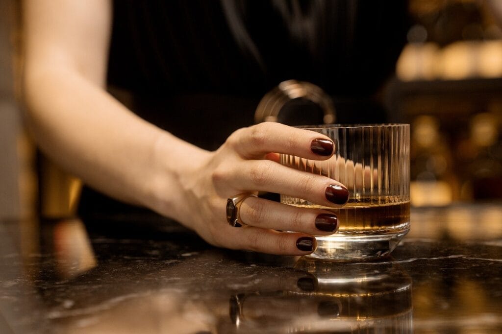 ¿Por Qué el Alcohol Nos Hace Perder la Memoria? 6 Mano de mujer sosteniendo vaso de whisky.