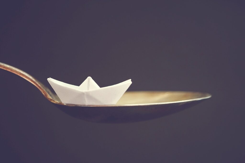 ¿Por qué flotan los barcos? 1 Barquito de papel en una cuchara. Fotografía macro de origami en miniatura.