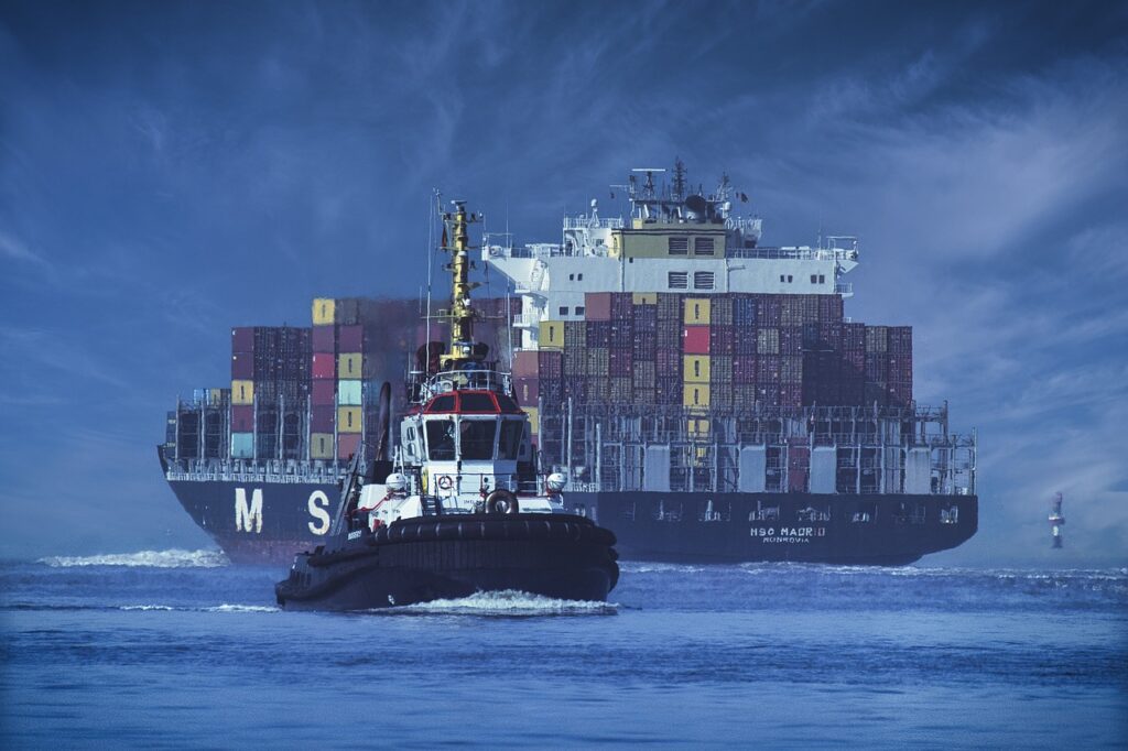 ¿Por qué flotan los barcos? 4 Remolcador asistiendo a buque portacontenedores. Imagen de barco remolcador guiando carguero gigante.