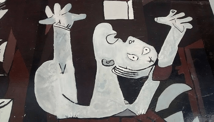 El significado oculto en dos grandes obras: "Alegoría del triunfo de Venus" y "Guernica" 7 "Fragmento de pintura cubista con figura blanca gritando y brazos levantados sobre fondo oscuro. Detalle artístico expresionista con formas geométricas y trazos audaces que evocan la desesperación. Obra de arte moderna con estilo vanguardista."