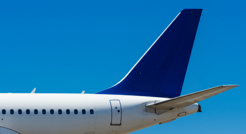 ¿Cómo es posible que un avión vuele? La ciencia detrás del milagro aéreo 6 Cola avión azul cielo. Imagen de la parte trasera de un avión blanco con la cola azul contra un cielo despejado. Transporte aéreo y aviación.
