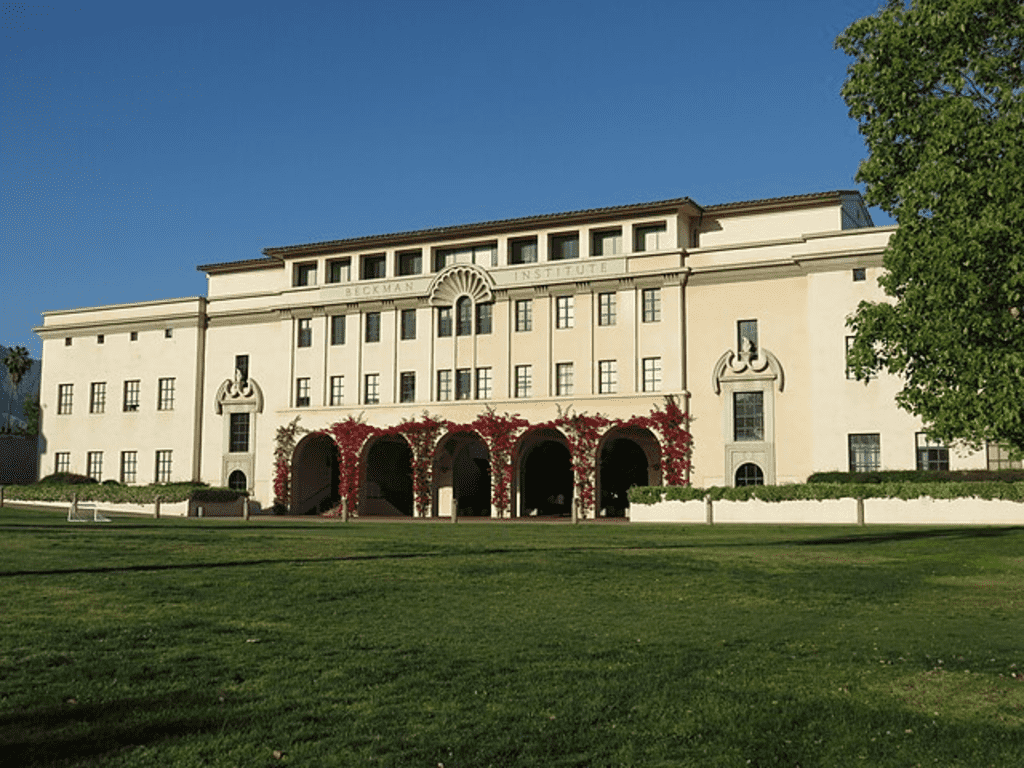 Las 10 Universidades Más Prestigiosas del Mundo y sus Costos de Matrícula 5 "Fachada del Instituto Beckman con césped verde y cielo azul despejado. Arquitectura simétrica y ambiente académico tranquilo. Ideal para universidades, arquitectura y SEO."