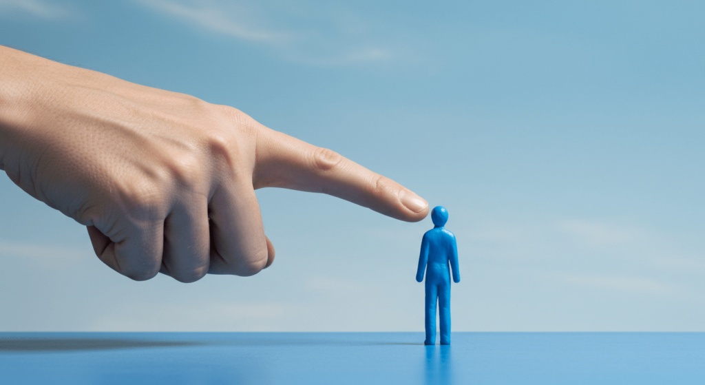 ¿Qué es la modernidad líquida? La teoría de un tiempo sin certezas 5 "Metáfora de poder: imagen conceptual de una mano grande apuntando a una figura pequeña azul, simbolizando dominio o rechazo. Ideal para contenido sobre poder, liderazgo y discriminación. Accesible para personas con discapacidad visual."