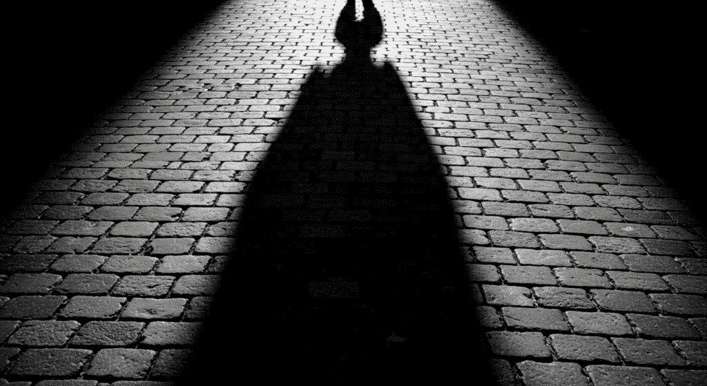 Curiosidades Sorprendentes sobre los Sueños que Probablemente No Sabías 4 "Sombra amenazante en calle empedrada. Imagen en blanco y negro de terror y misterio para SEO y accesibilidad."