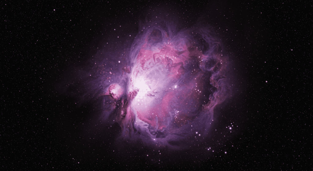 La Antimateria y sus posibles aplicaciones 6 Imagen de una nebulosa púrpura y rosa en el espacio con un fondo de estrellas brillantes. Representación visual de astronomía, galaxias y el universo.