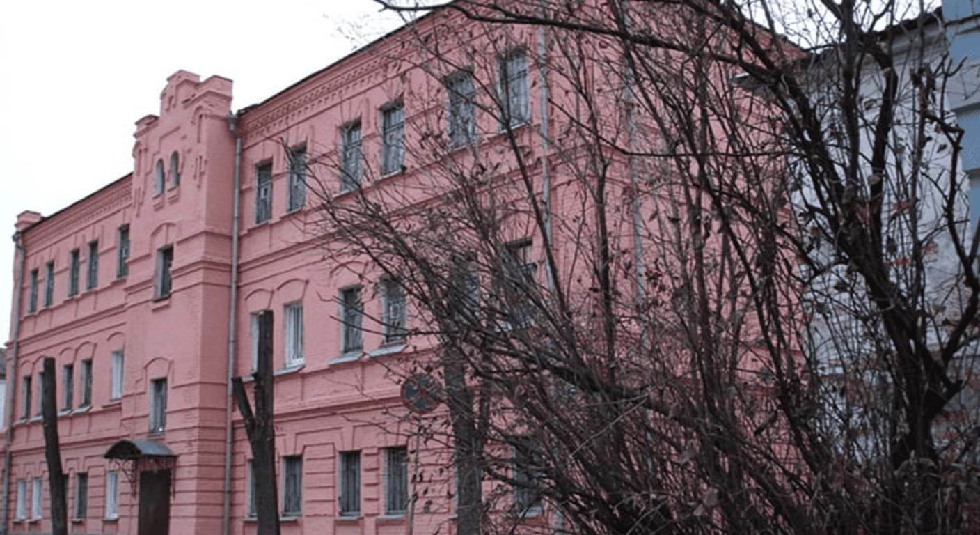 Las cárceles más peligrosas del mundo: Supervivencia, violencia y brutalidad 6 Edificio de ladrillo rosa con árbol en primer plano. Imagen de arquitectura urbana con fachada llamativa ideal para contenido sobre diseño urbano y edificios singulares.
