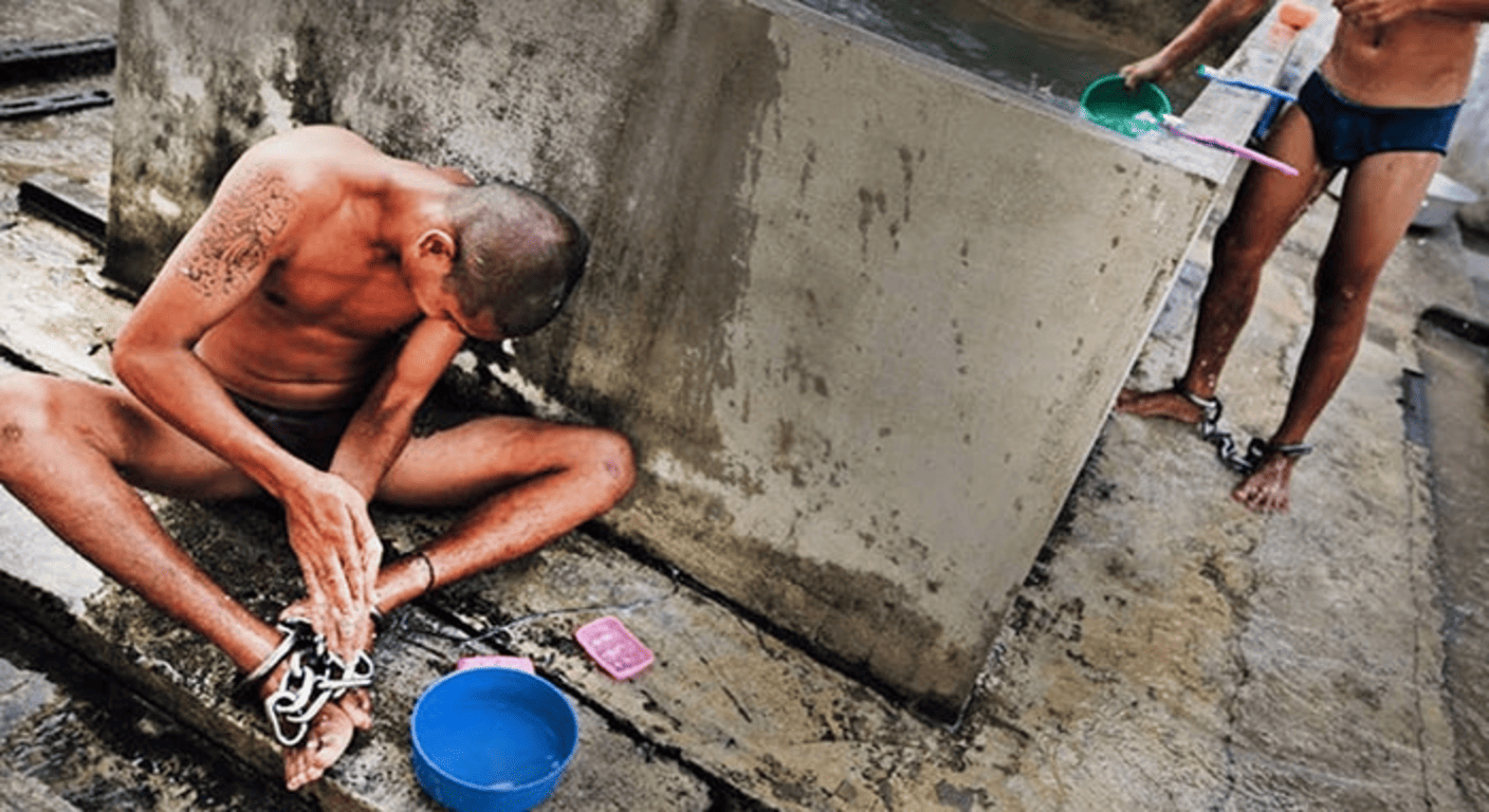 Las cárceles más peligrosas del mundo: Supervivencia, violencia y brutalidad 2 Imagen de dos hombres encadenados lavándose en un área exterior. Fotografía que puede reflejar condiciones de vida difíciles o de explotación.
