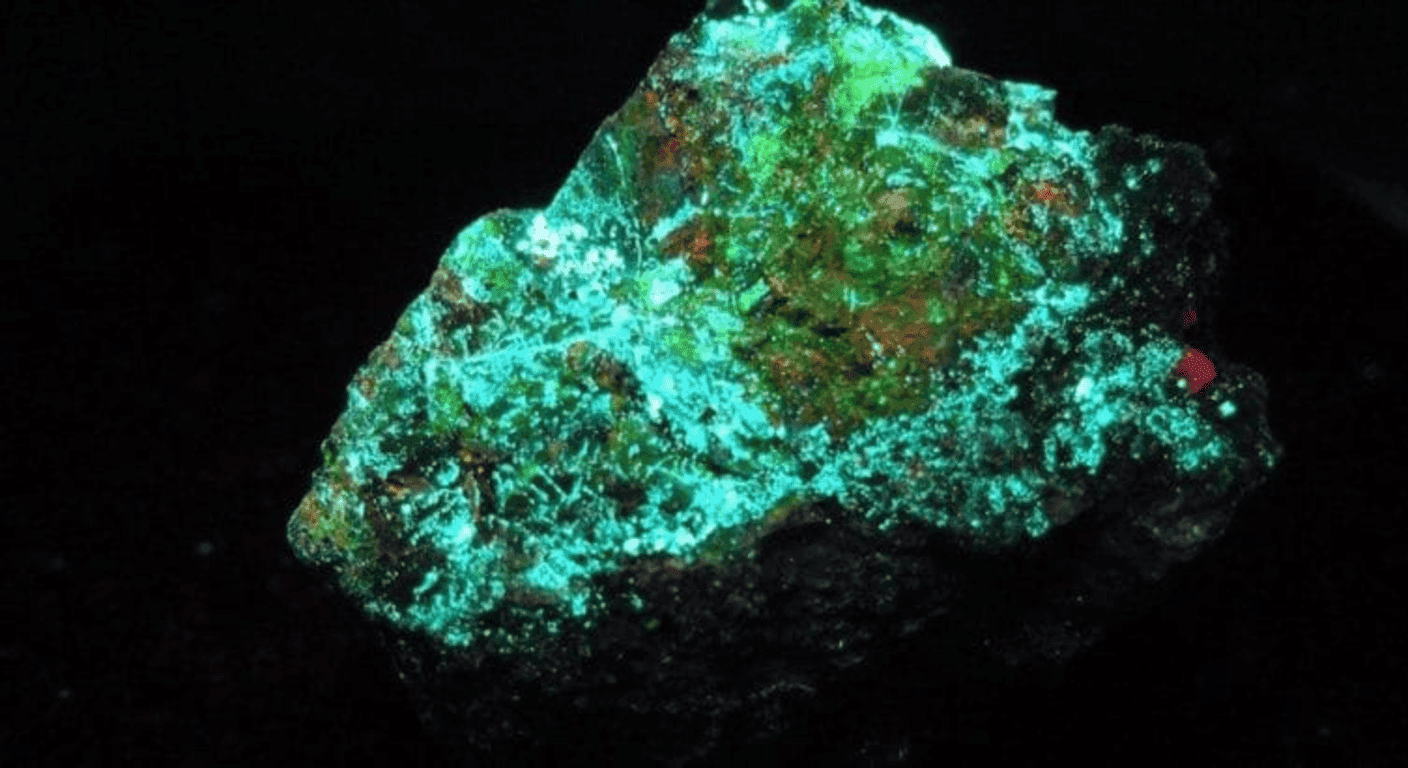 Radiación: qué es, cómo funciona y por qué es tan importante 3 "Mineral fluorescente brillando en verde. Roca luminiscente con destellos de color contra fondo negro. Mineralogía, geología, fluorescencia, fosforescencia, piedra preciosa."