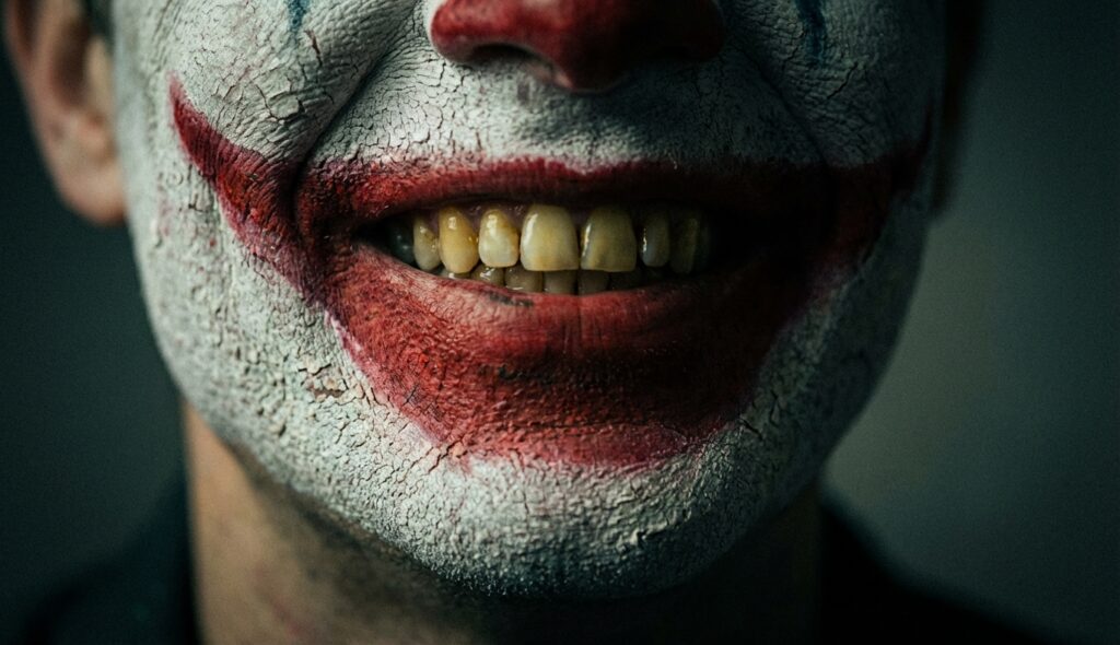 Primer plano de una sonrisa de payaso siniestra con pintura agrietada